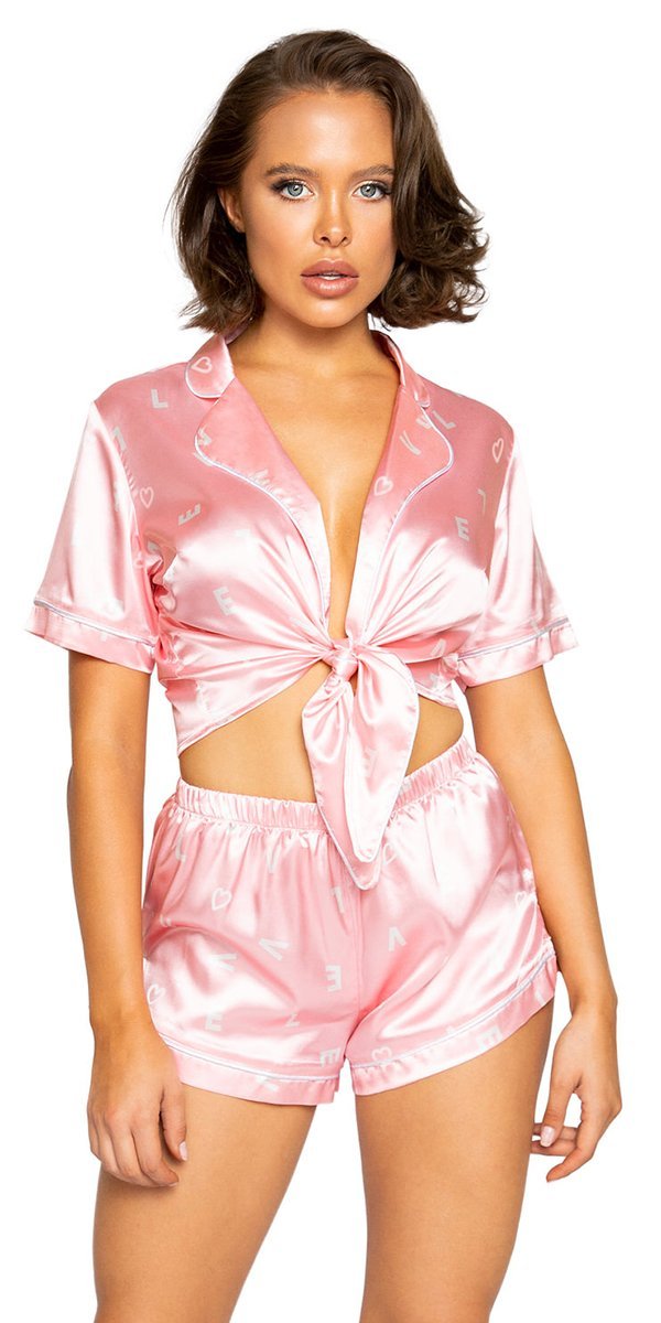 A woman wearing pink pajamas with a close-up of a pink bow. The scene suggests a fashion model in a photo shoot setting.