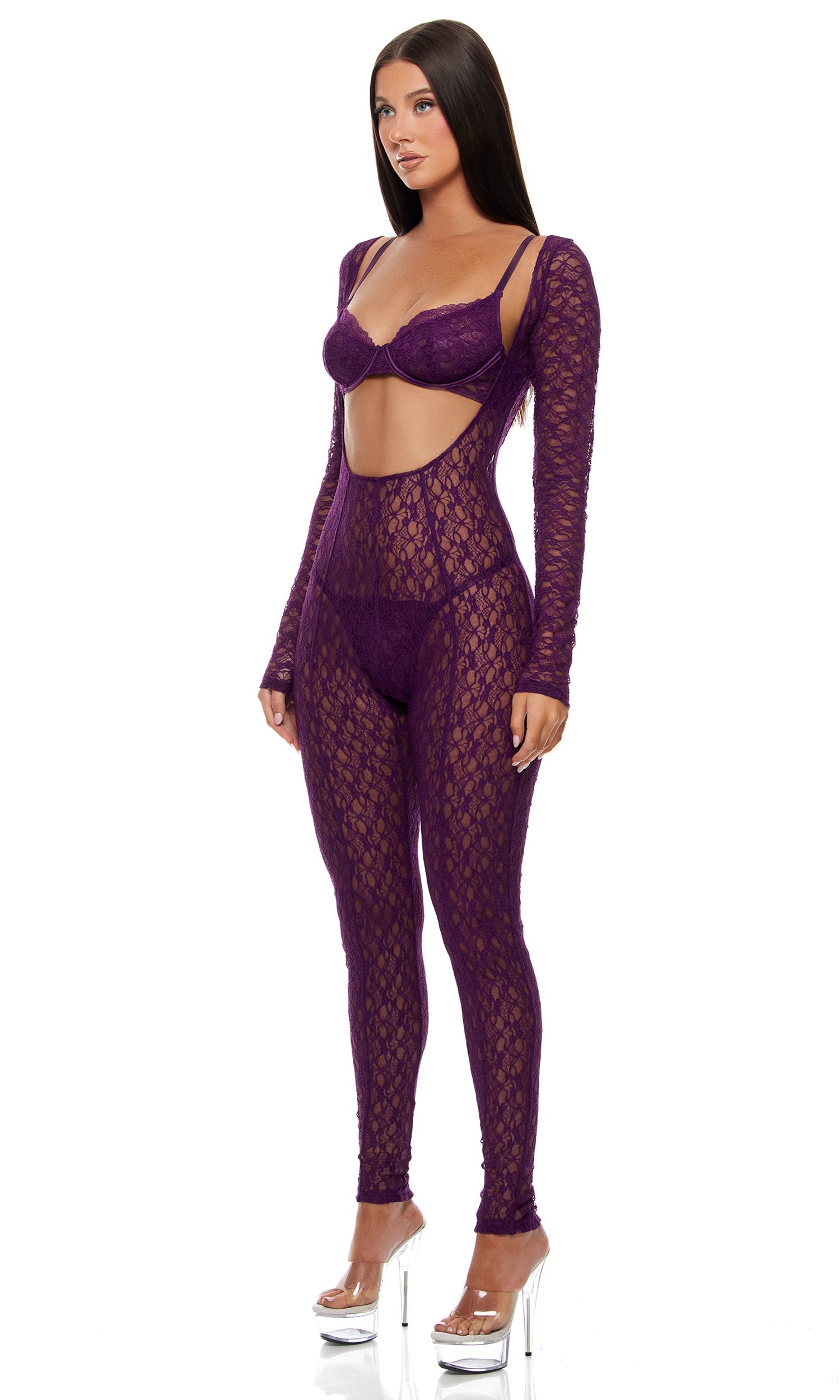 Feel Me Textured Lace Jumpsuit Lingerie Set features a purple lace bodysuit with bra-style top, cut-out midriff, and matching G-string panty, complemented by clear platform stiletto heels.