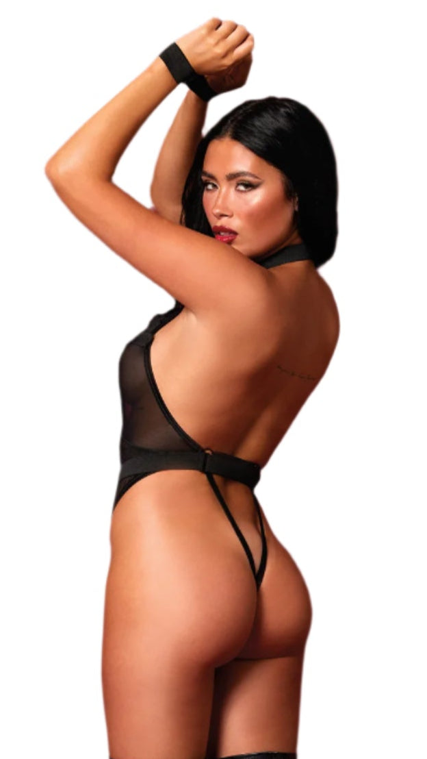 Woman modeling a stretch mesh teddy with halter neck, plunging neckline, elastic X-straps, gold accents, high-leg G-string, and adjustable back straps, featuring wrist restraints.