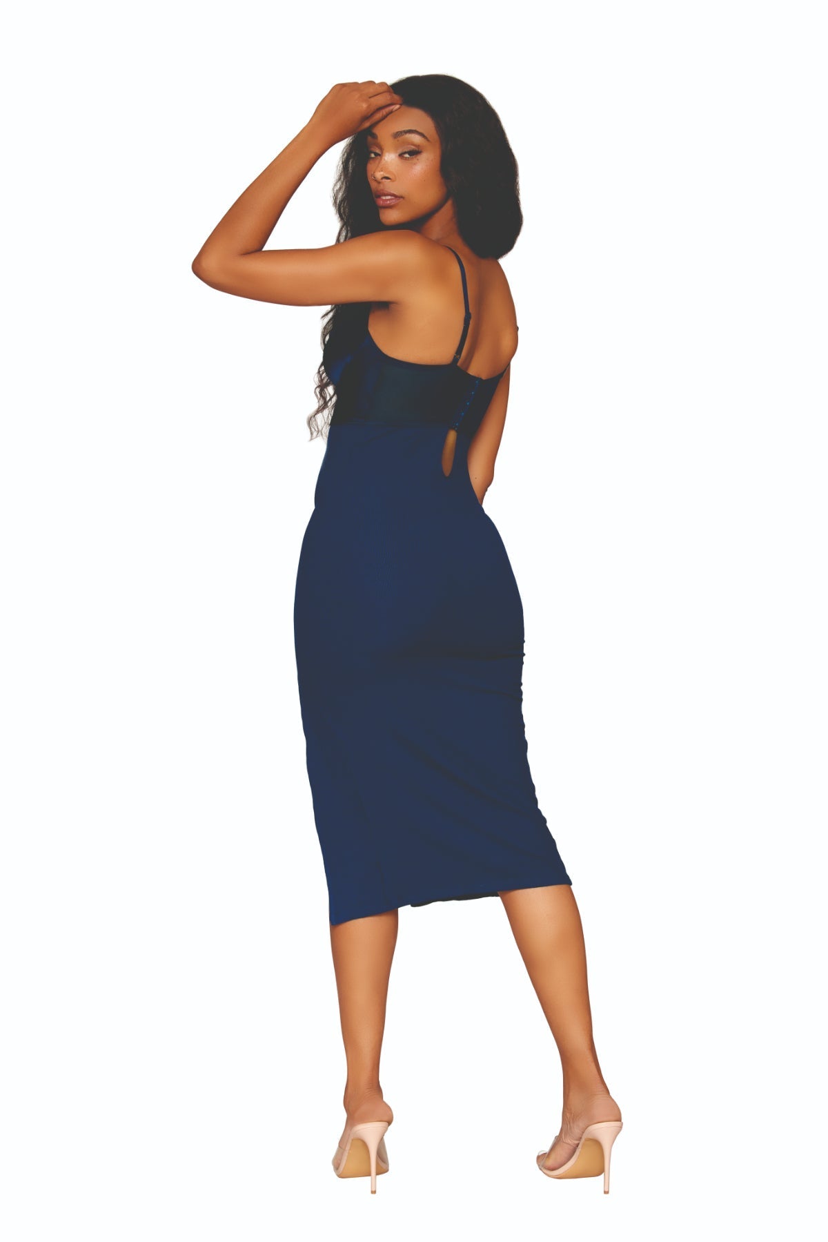 A woman with long, wavy hair smiles while wearing a stylish outfit. She is dressed in a dark blue Stretch Satin Rib Knit Midi Sleep Chemise with a high front slit, paired with high-heeled platform sandals. She accessorizes with multiple necklaces, bracelets, and rings.