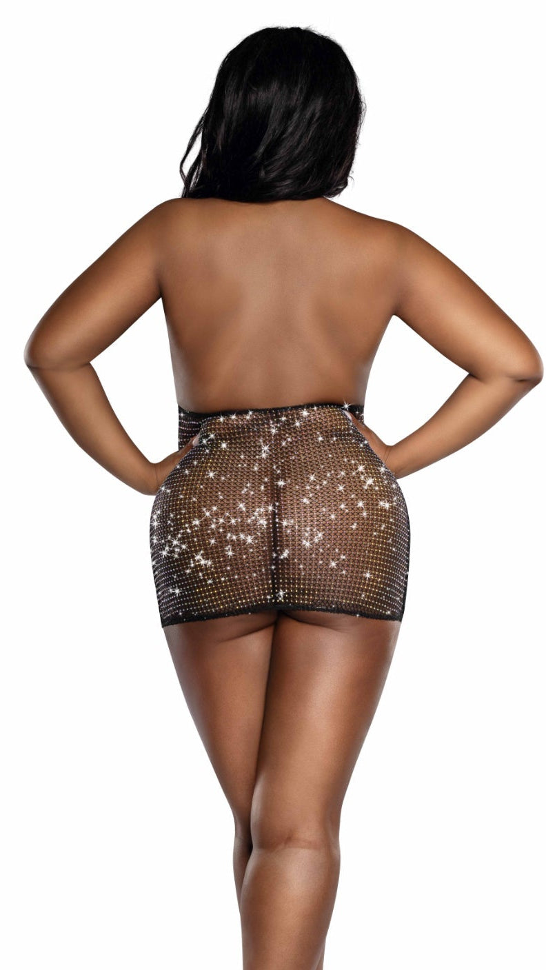 Rear view of a woman in a Plus Size Shine Bright cowl neck rhinestone fishnet mini dress, featuring a black sheer mini-skirt with sparkling studs, paired with black patent-leather high heels.