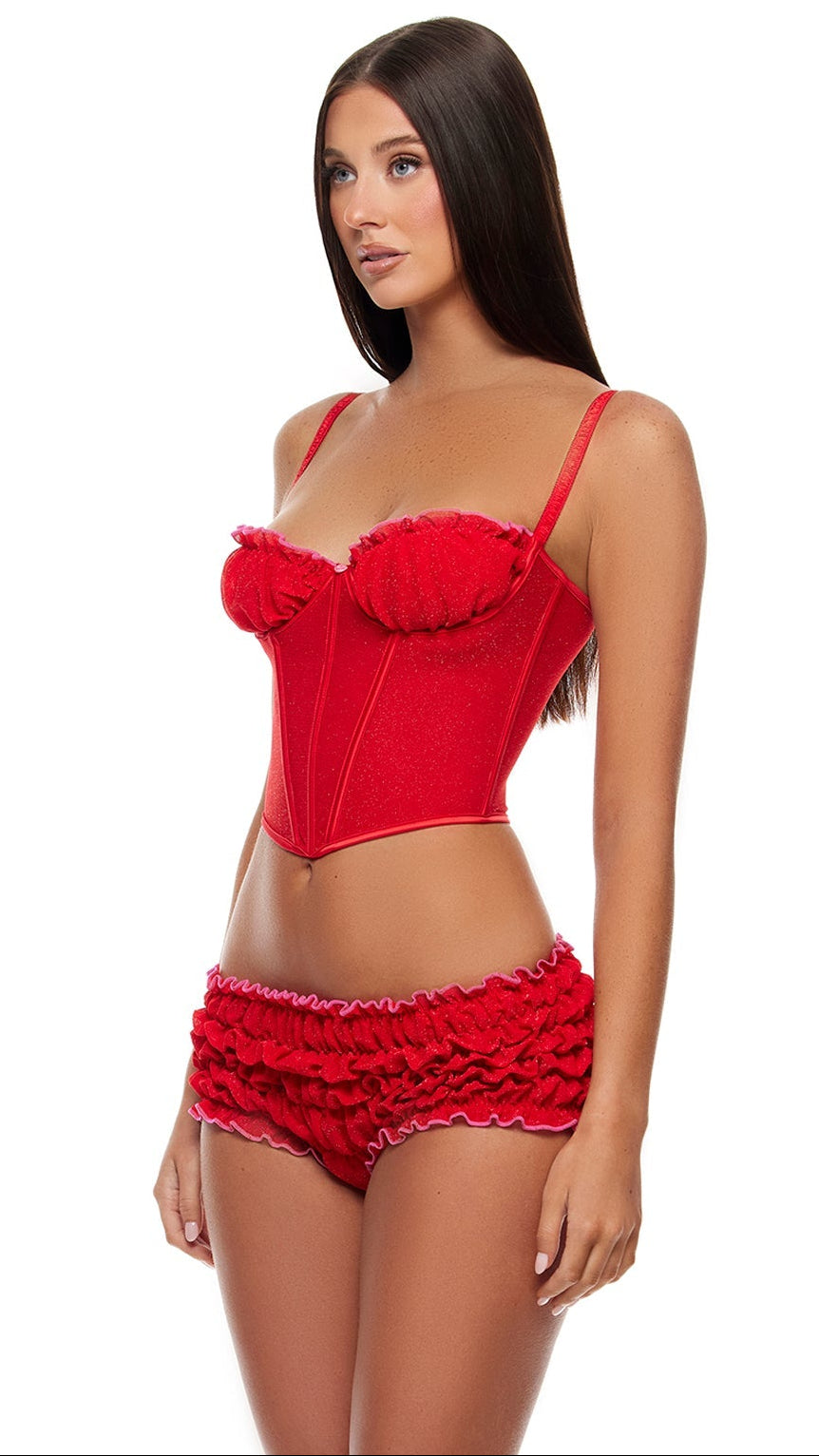 Shimmer Nights Ruched Bustier Lingerie Set features a structured underwire bustier with boning, lettuce edge details, and a rosebud accent, paired with matching ruched bloomer shorts, modeled by a long-haired woman.