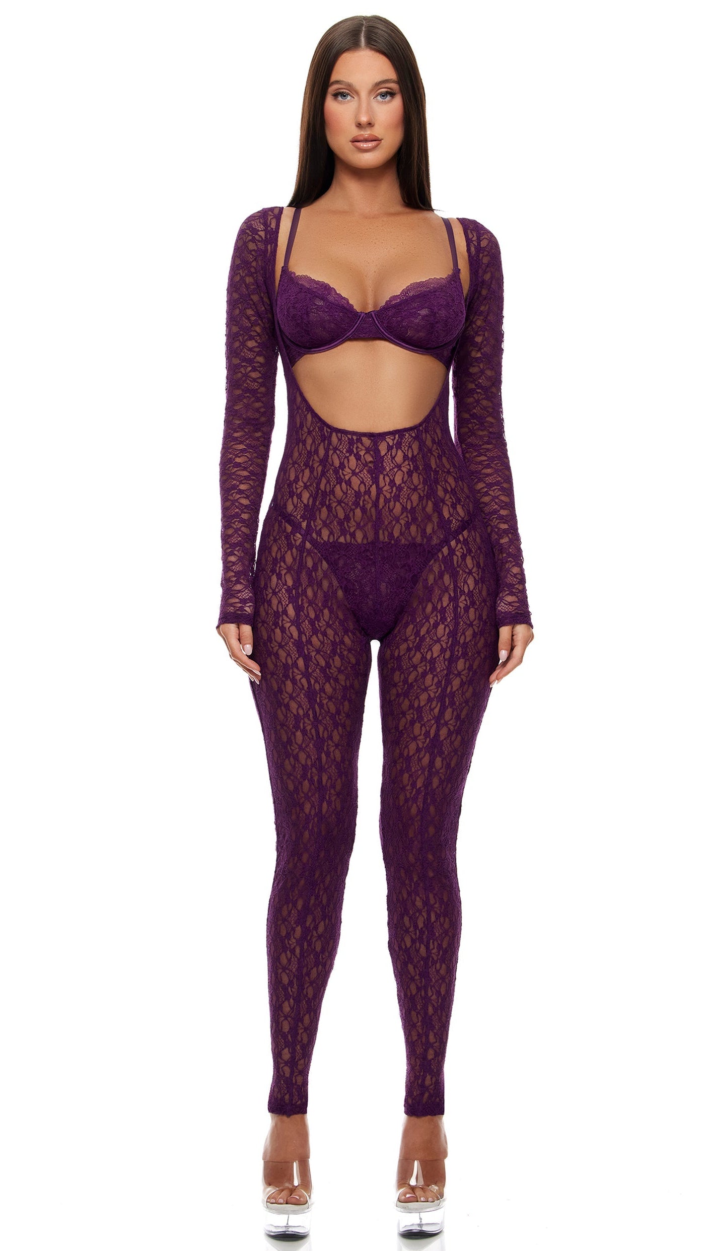 Feel Me Textured Lace Jumpsuit Lingerie Set featuring a sheer lace bodysuit with cut-out midriff, long sleeves, over scallop lace bra, and matching G-string panty. Model wears clear-platform heels.